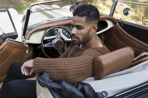Man in bruine gebreide trui in een klassieke cabriolet
