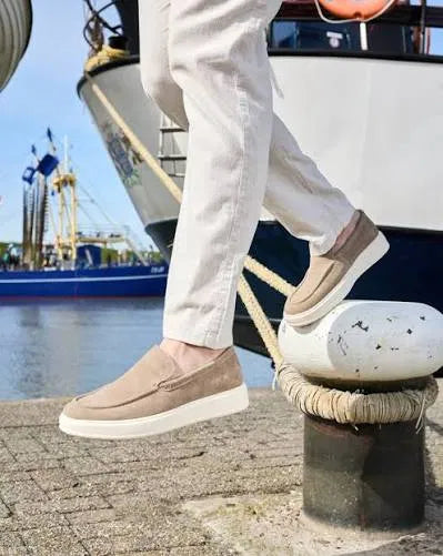 Beige suède herenschoenen op een kade bij de haven